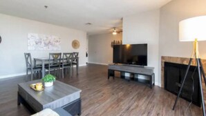 A spacious living room with a flat-screen TV, a fireplace, and a dining area with chairs and a table.