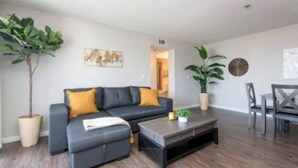 A modern living room with a grey sofa, a coffee table, and two potted plants.