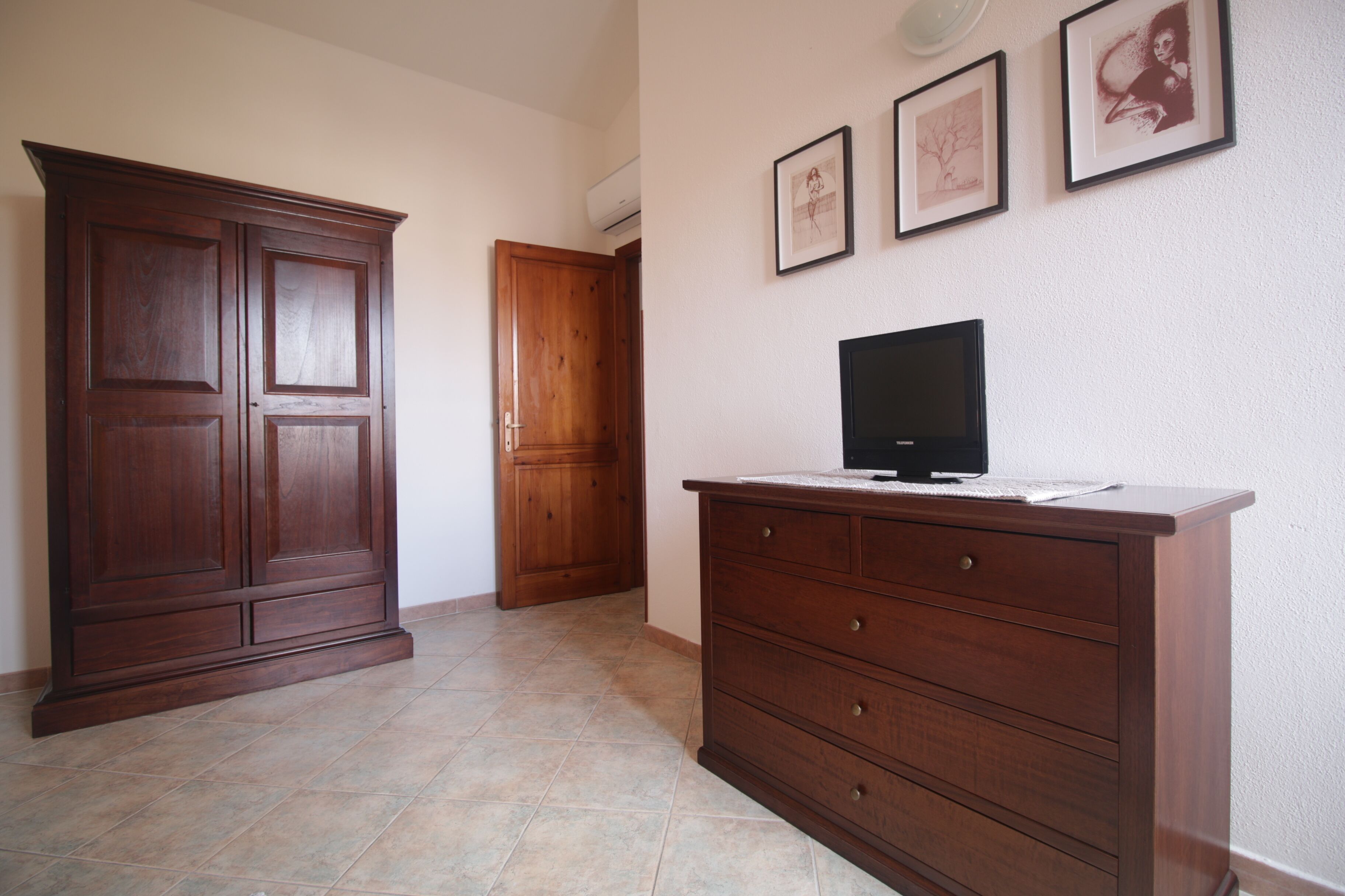 Un corridoio con un'armadiatura in legno, una televisione su un comò e quadri appesi al muro.