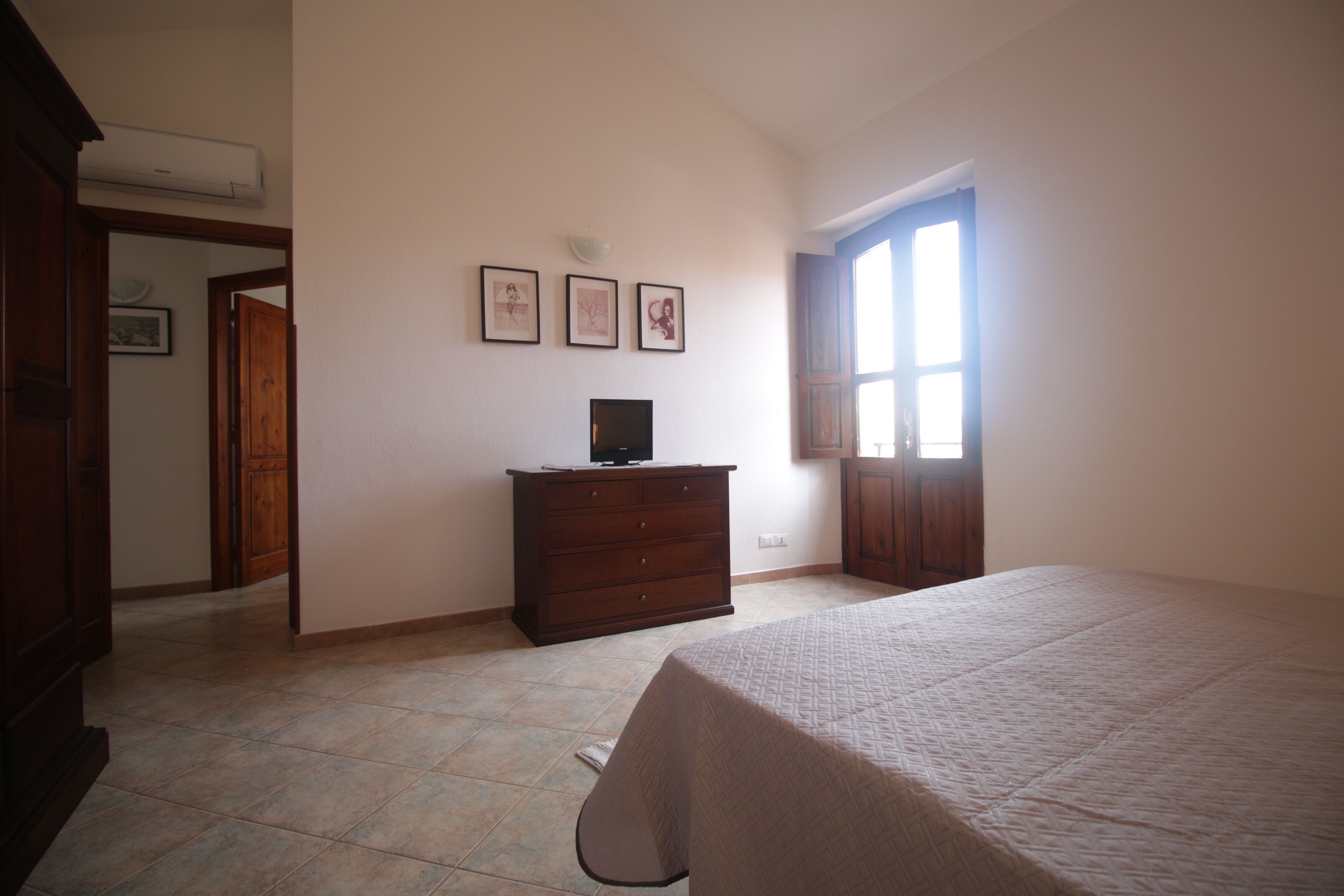 Una camera da letto con un letto, una cassettiera e una finestra.