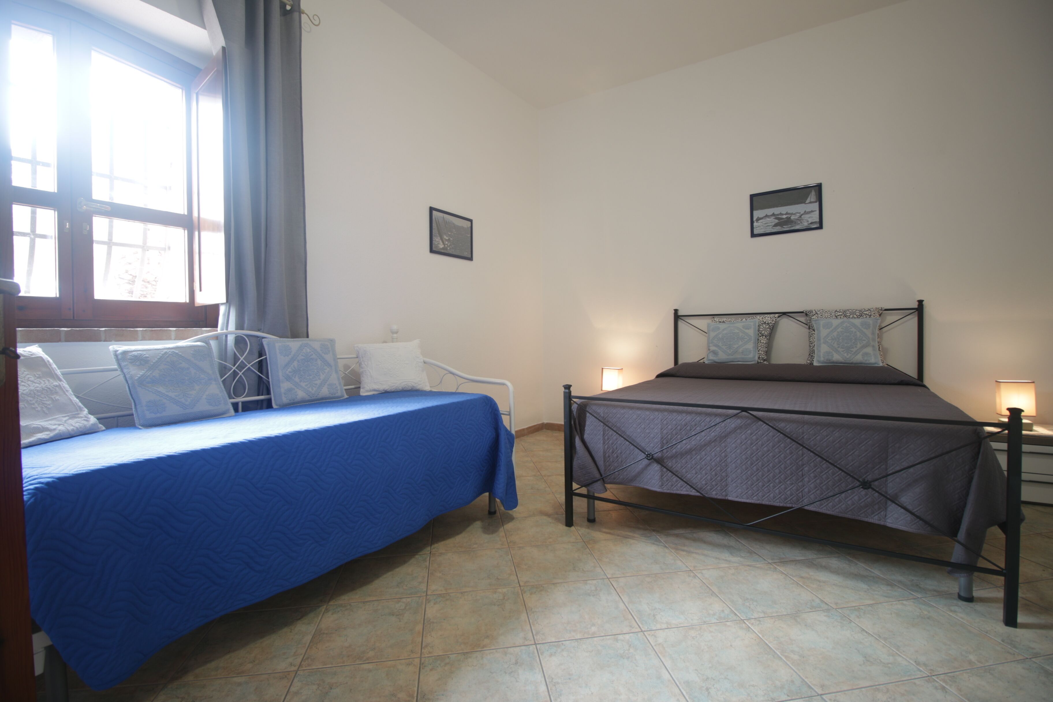 Un dormitorio con una cama, una ventana con cortinas y un cuadro colgado en la pared.