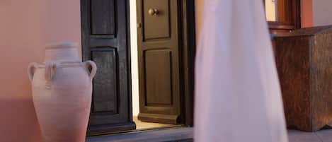 A large white vase and a smaller vase in front of a dark wooden door.