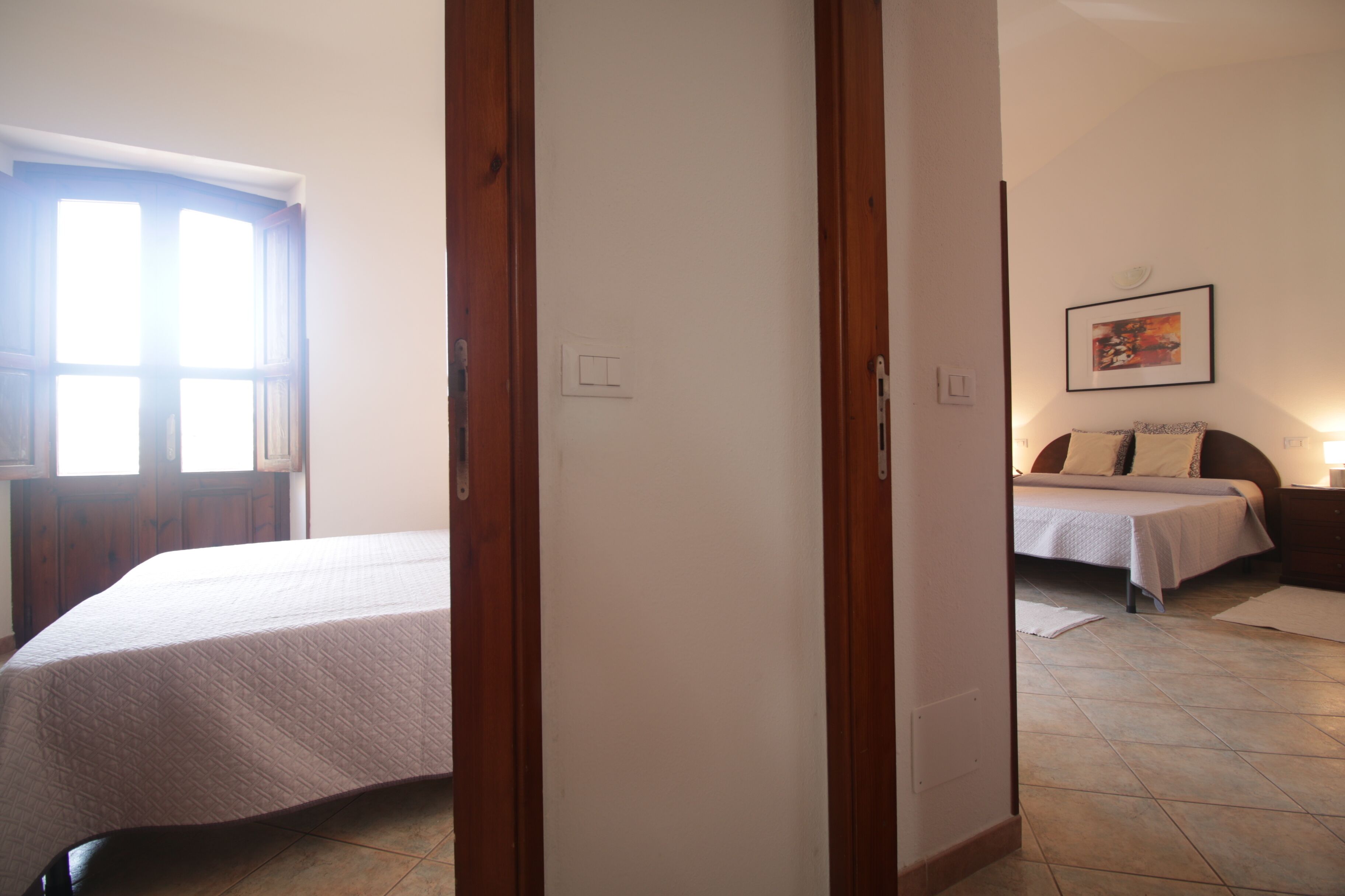 Un dormitorio con una cama, un mesita de noche y una ventana.