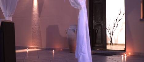 A dimly lit hallway with a tiled floor, a large vase, and a door leading to another room.