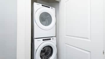 A stacked washer and dryer unit in a white-walled room.