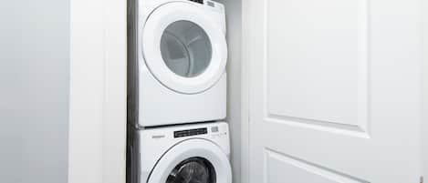 A stacked washer and dryer unit in a white-walled room.