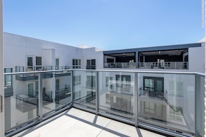 Ein modernes Gebäude mit einem Glasbalkon, zahlreichen Fenstern und einem Flachdach.