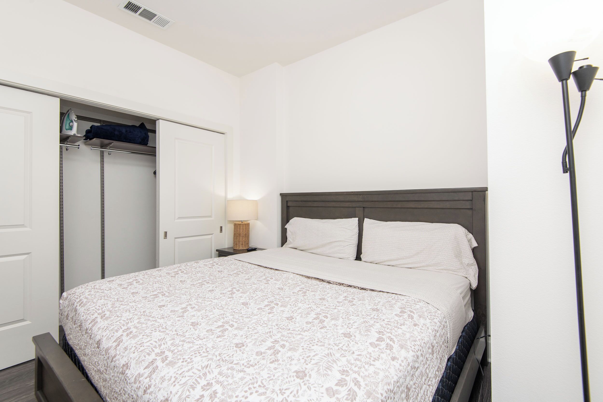 A bedroom with a bed, a wardrobe, a nightstand, and a lamp.