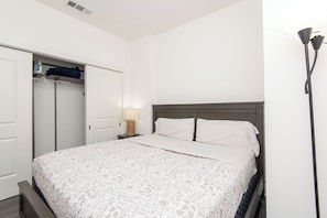 Ein Schlafzimmer mit Bett, Kleiderschrank, Nachttisch und Lampe.