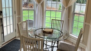A dining area with a glass table, white chairs, a clock, and a view of a backyard. - Large private home near campus (Auburn)
