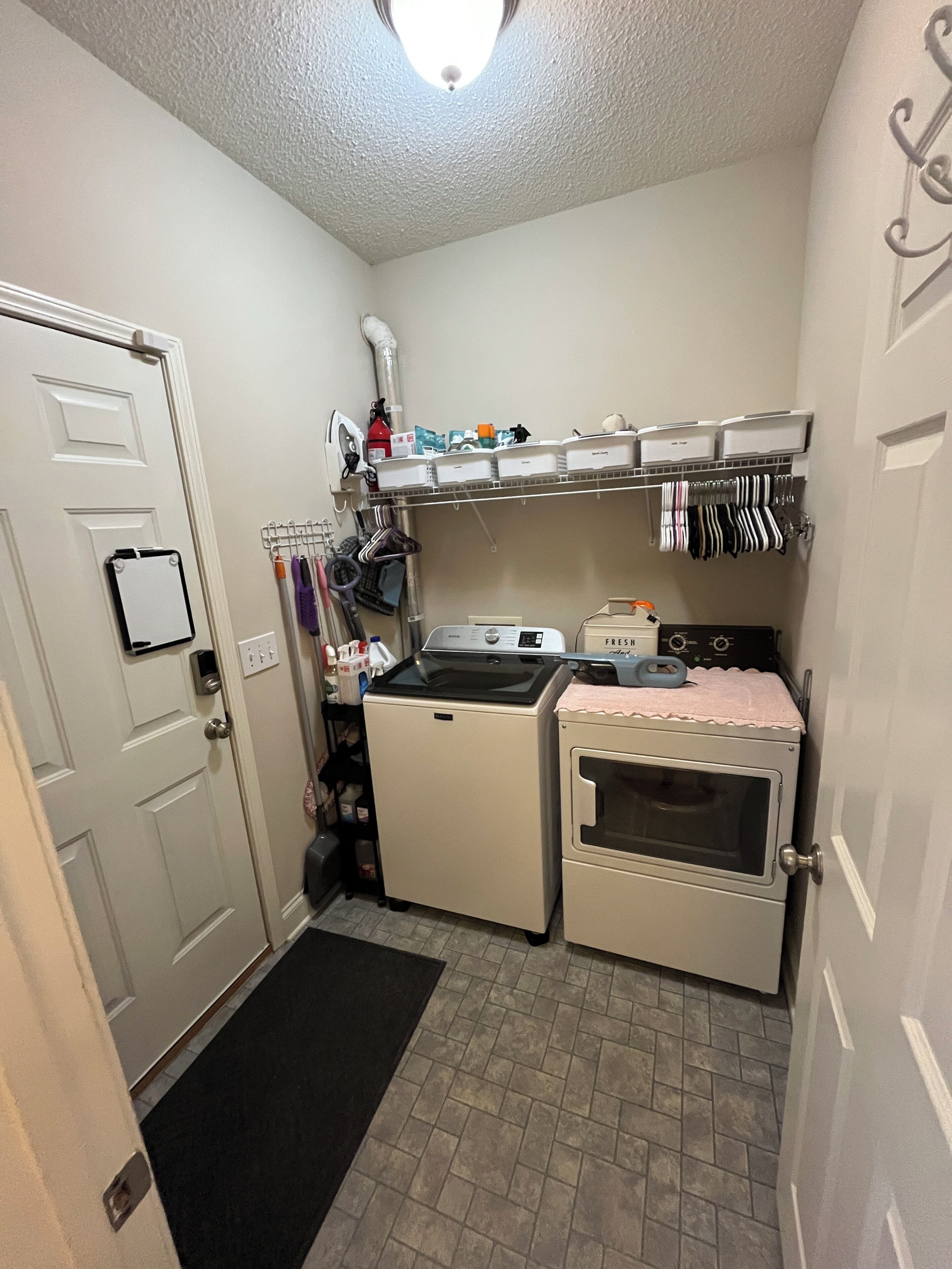A compact kitchen with a washing machine, dryer, and a small countertop with various items.