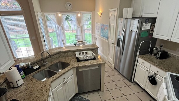 A kitchen with granite countertops, stainless steel appliances, and a view of a backyard through large windows. - Large private home near campus (Auburn)