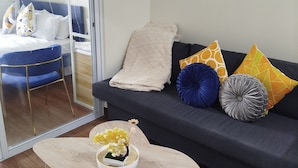 Una sala de estar moderna con un sofá azul oscuro, una mesa de centro de color claro y un puerta de cristal que da a un balcón.
