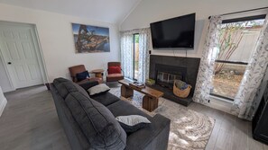 A living room with a sofa, chairs, a TV, a fireplace, and a painting on the wall.