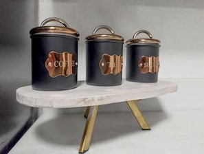 Tres recipientes de café negro con tapas de cobre sobre una mesa de mármol blanco.