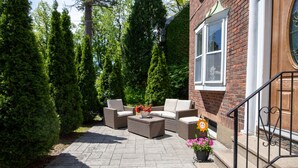 Une terrasse avec des meubles d’extérieur, une plante en pot et une porte en bois.