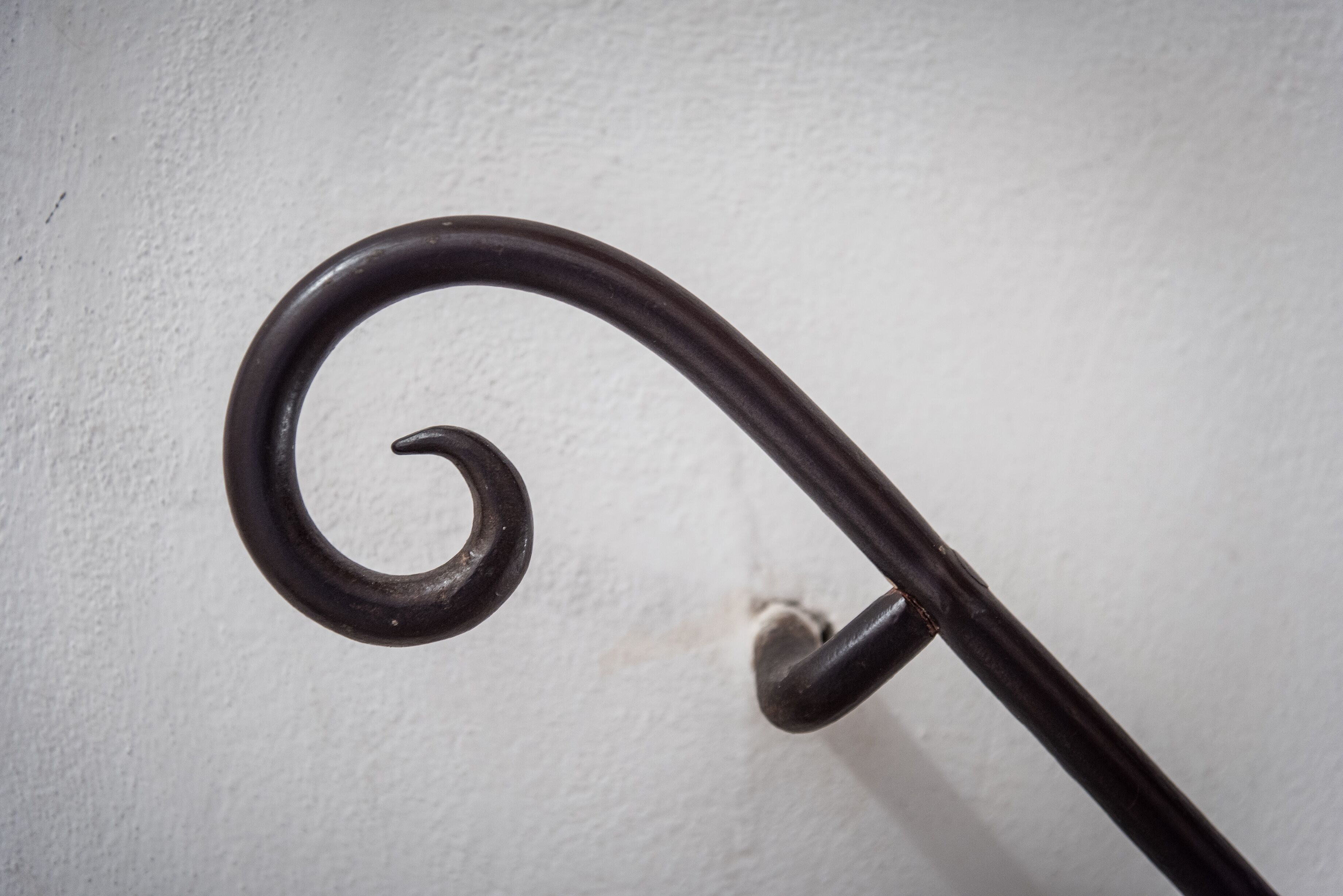 Ein Detailaufnahme einer Metall-Wendeltreppe vor einer weißen Wand.