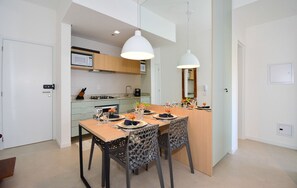 A modern kitchen with a dining area, featuring a central island, pendant lights, and a large mirror. - SunClub-300 metros da Praia do Campeche (Florianopolis)