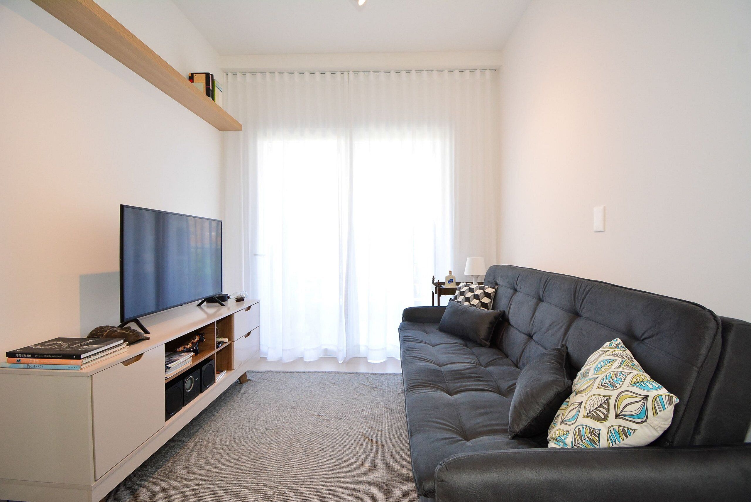 A living room with a flat-screen TV, a dark sofa, and a white entertainment unit.