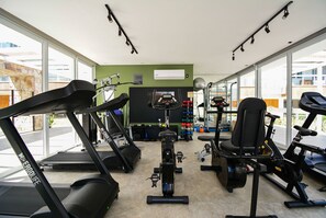 Une salle de sport équipée de tapis de course, de vélos d’appartement et d’autres appareils d’exercice.