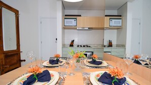 Une table à manger dressée pour quatre personnes, agrémentée de centres de table floraux, un four à micro-ondes placé au-dessus du comptoir et une porte en bois sur le côté gauche.