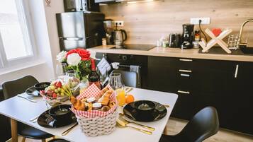 A breakfast setup with a table set for two, including plates, bowls, glasses, and a basket of bread and fruit.