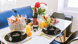 A breakfast setting with croissants, fruit, wine, and orange juice on a white table. - Le Sam PLay (Mussidan)
