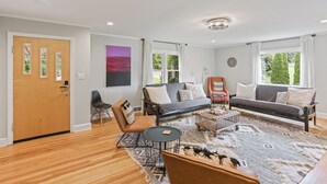 A modern living room with a sofa, chairs, a coffee table, and a rug.