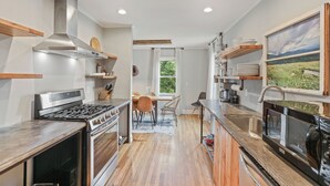 A modern kitchen with a stove, oven, and microwave. There is a dining area with a table and chairs.