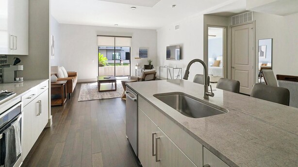 A modern kitchen with a large island, built-in appliances, and a sliding glass door leading to a balcony. - Landing Apartments Houston (Houston)
