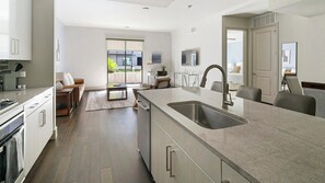 A modern kitchen with a large island, built-in appliances, and a sliding glass door leading to a balcony. - Landing Apartments Houston (Houston)