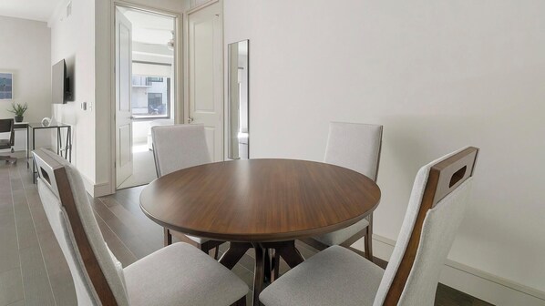 A modern dining area with a round wooden table surrounded by six upholstered chairs. - Landing Apartments Houston (Houston)