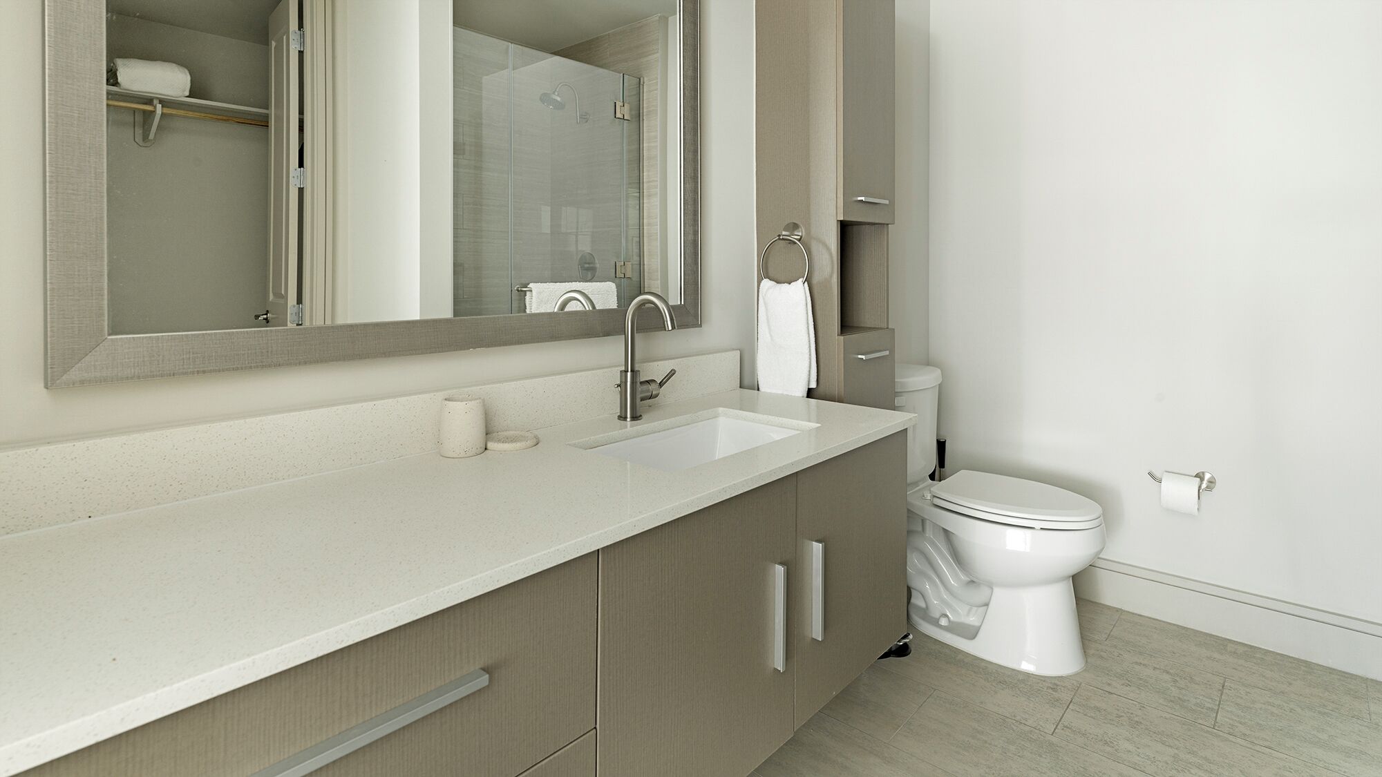 A modern bathroom with a large mirror, a sink, a toilet, and a shower area.