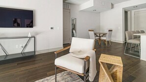 Una sala de estar moderna con un sofá blanco, una mesa de centro de madera y un comedor con una mesa redonda y sillas.