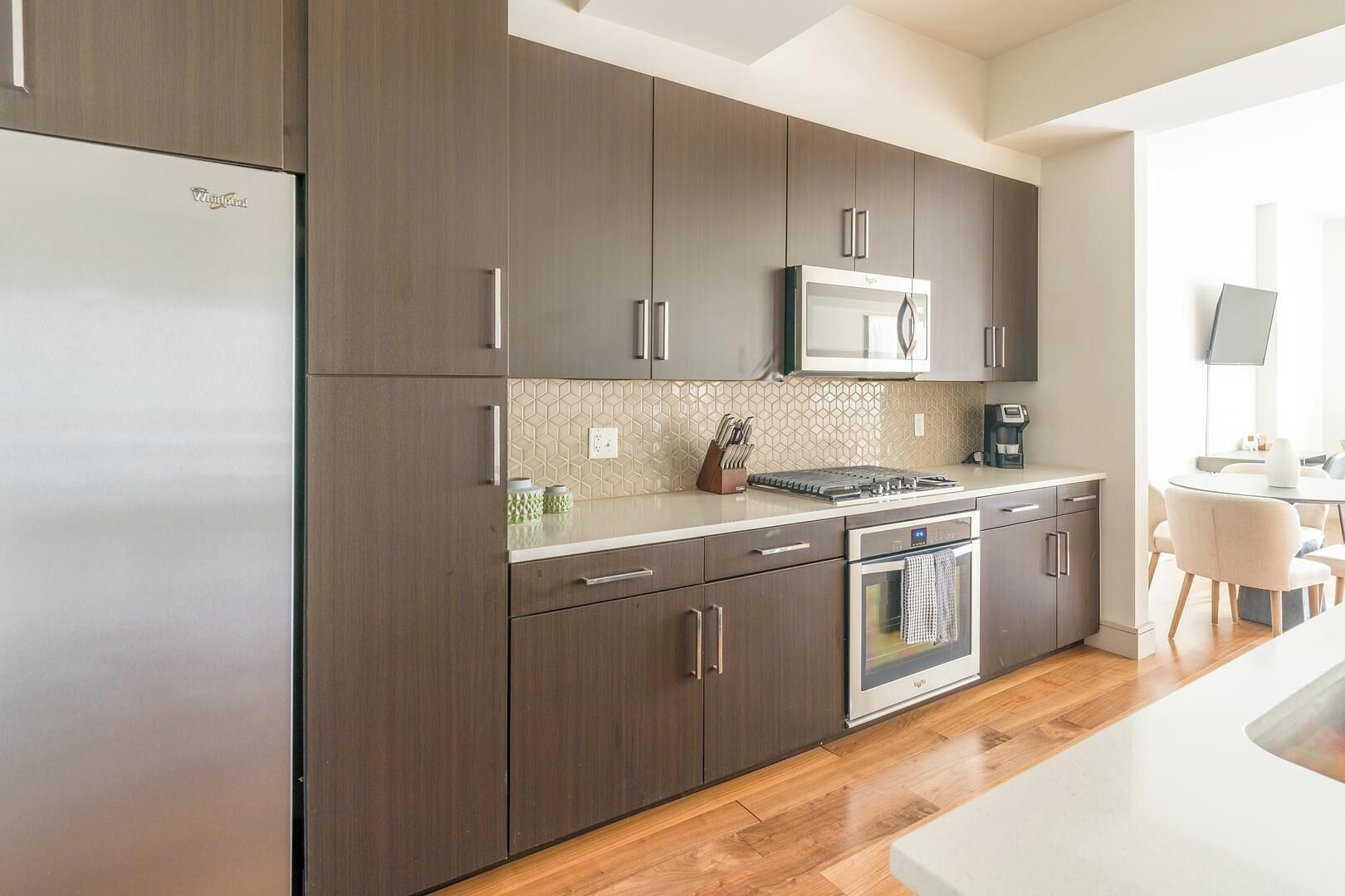 A modern kitchen with dark wood cabinets, a stainless steel refrigerator, a microwave, and an oven.