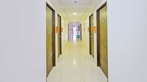 A long, narrow hallway with doors on both sides, leading to a central area with a trash bin and a fire extinguisher. - OYO 1144 1318 Residences (Manila)