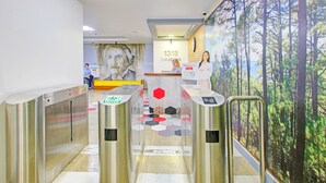 A reception area with a large mural, a reception desk, and a security checkpoint. - OYO 1144 1318 Residences (Manila)