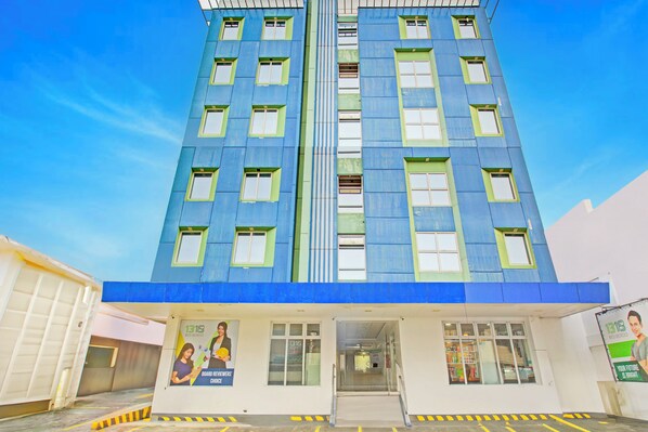 A modern building with a blue facade, multiple windows, and a visible entrance.