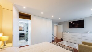 A modern bedroom with a large bed, a TV mounted on the wall, and a walk-in closet. - Spacious and comfortable apartment in Apulia, 100 m from the beach! (Apúlia)