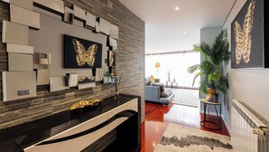 A modern living room with a black and white decor, a large butterfly artwork, and a potted plant. - Spacious and comfortable apartment in Apulia, 100 m from the beach! (Apúlia)