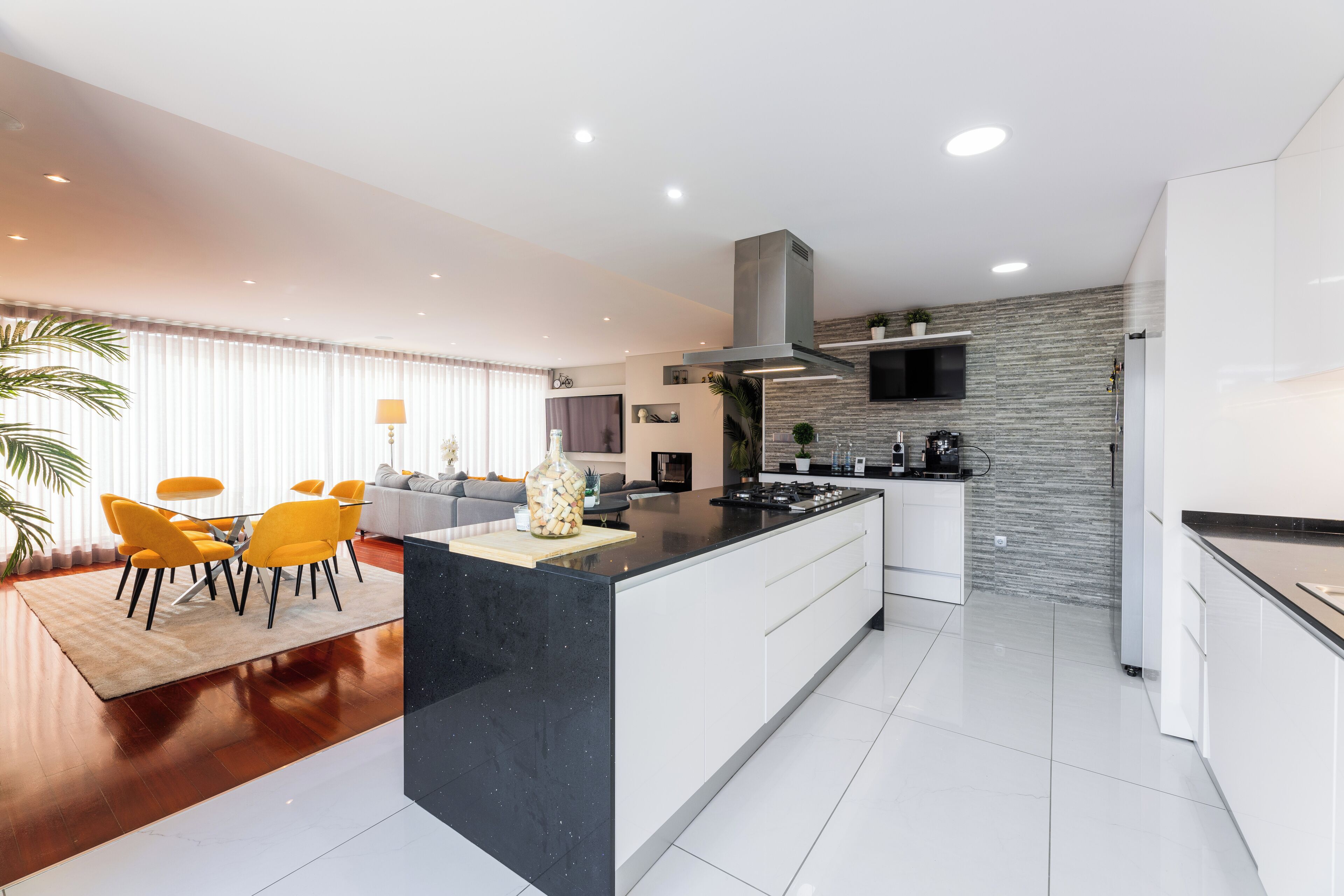 A modern kitchen with a central island, white cabinetry, and a stone backsplash.
