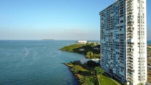 Un hotel modern amb molts balcons, vista al mar i una petita illa a la distància.
