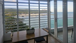 Un balcó amb taula i cadires, que ofereix vistes a un port esportiu i a la costa.