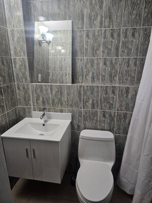 A bathroom with a white sink, a toilet, and a shower curtain. - Concho Toad Bay (Fajardo)
