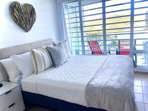 A bedroom with a bed, pillows, a nightstand, and a heart-shaped decoration on the wall. - Concho Toad Bay (Fajardo)