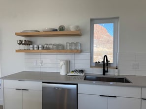 Una cocina moderna con lavavajillas, un fregadero y una ventana con vistas a un paisaje desértico.