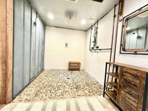 A room with a patterned floor, a wooden bench, a metal shelf, and a window with a metal frame.
