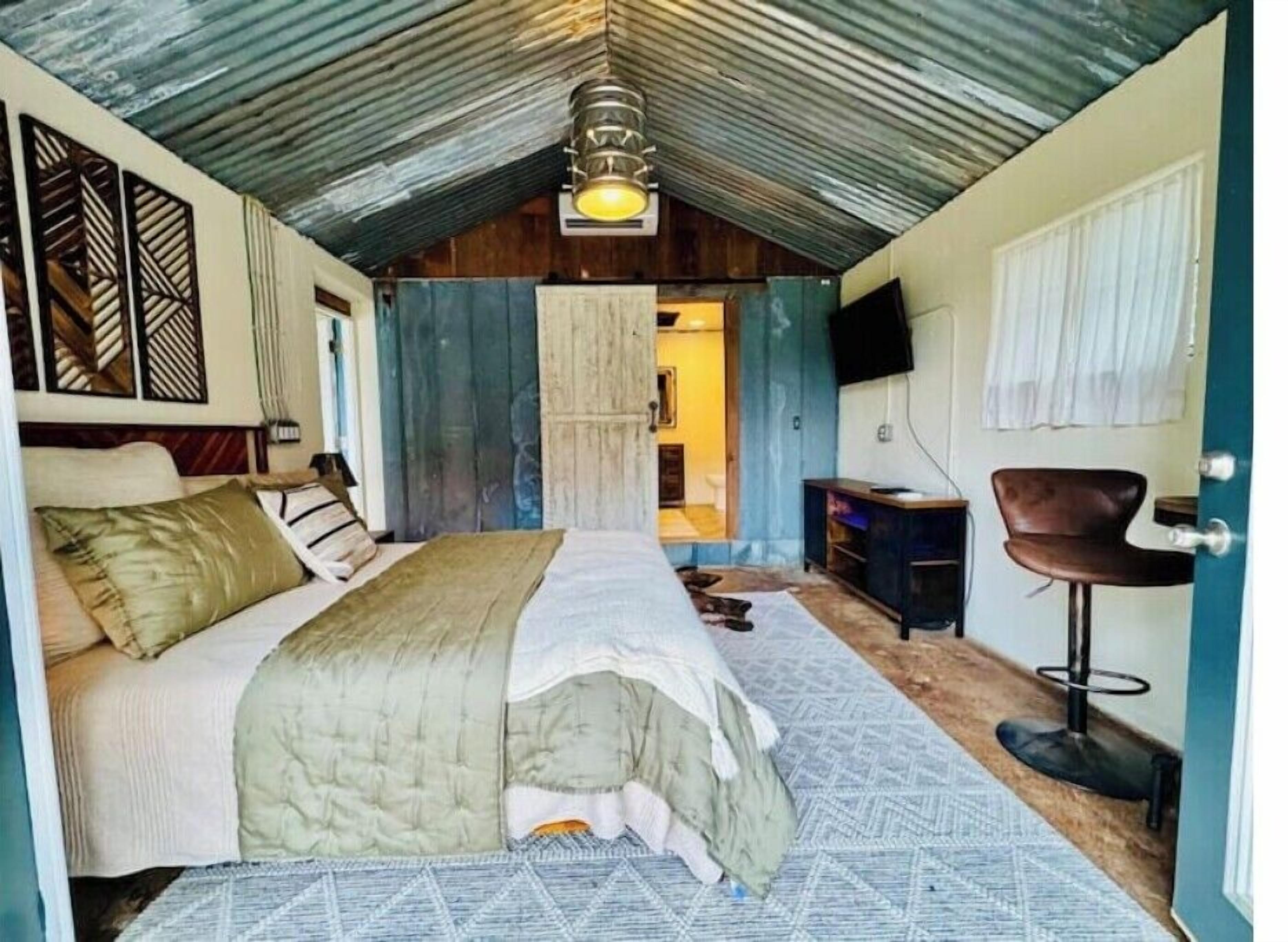 A bedroom with a bed, a desk, a chair, and a television.
