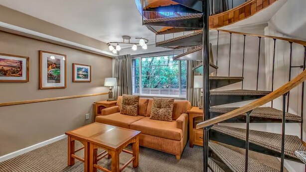 Un salon avec un canapé, une table basse et un escalier doté d’une rampe en bois.