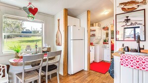 Cozinha compacta com geladeira, armários de madeira e um espaço de refeições com cadeiras e mesa.